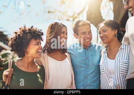 Wir sind eine enge Gruppe von Freunden. Eine fröhliche junge Gruppe von Freunden, die tagsüber Arm in Arm eine Straße entlang gehen. Stockfoto