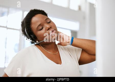 Gestresst, Nackenschmerzen und müde Callcenter-Mitarbeiter, die sich während der Arbeit mit dem Headset schlechte, strapazierte oder schmerzende Muskeln ausstrecken. E-Commerce-Unterstützung für Frauen Stockfoto
