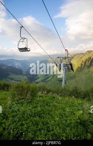 Die vertikale Ansicht von Telecabin, die an einem sonnigen Tag über die grünen Hänge führt Stockfoto