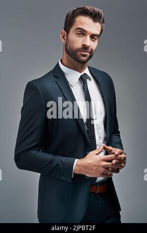 Erfolg in seinem Schritt. Studioporträt eines hübschen jungen Geschäftsmannes, der vor grauem Hintergrund posiert. Stockfoto