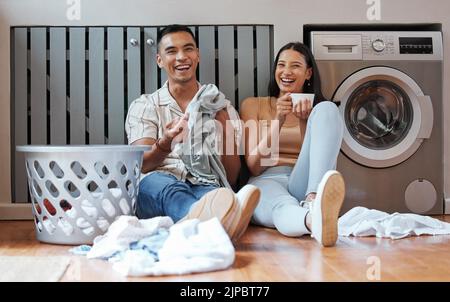 Glückliches, entspanntes und verantwortungsbewusstes Paar, das am Wochenende zu Hause Wäsche waschen, Hausarbeiten erledigen oder gemeinsam putzen kann. Junge tausendjährige Freund und Stockfoto