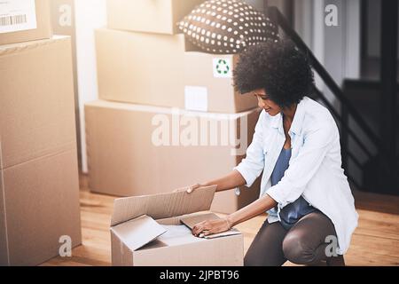 Lassen Sie das Auspacken beginnen. Eine attraktive junge Frau, die in ihrem neuen Zuhause Boxen auspacken will. Stockfoto