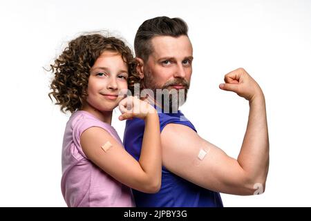 Familie in einfachen T-Shirts mit Bizeps mit Band-Aid nach Impfstoffinjektion. Vater und Tochter 10-12s tragen pinke und violette T-Shirts auf weißem Studio Stockfoto