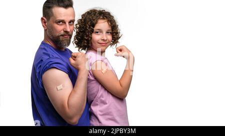 Familie in lässigen T-Shirts mit Bizeps und Bandenhilfe nach Impfstoffinjektion. Vater und Tochter 10-12s in rosa und violetten T-Shirts auf weißem Studio Stockfoto