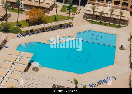Luftaufnahme eines großen Swimmingpools in einem luxuriösen tropischen Hotel mit Sonnenliegen Stockfoto