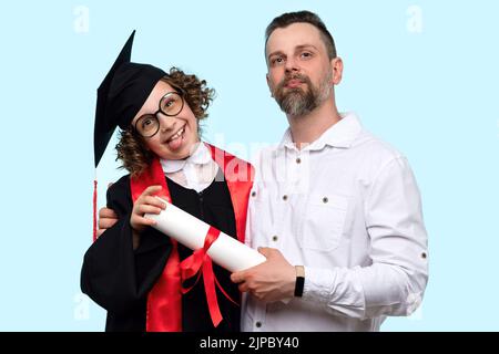 Fröhliche weibliche Kind in Abschlusskappe und Zeremonie Robe hält Zertifikat hat Spaß mit dem Vater auf hellblauen Studio Hintergrund. Vater gratuliert prodi Stockfoto