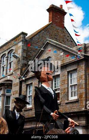 Riesige Machenfiguren aus Papier werden die Straße runter in Penzance für den Golowan-Mazey-Tag verarbeitet Stockfoto