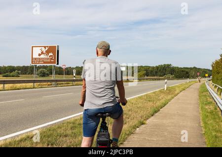 Domtiz, Deutschland - 2. August 2022: Tourist beobachtet das Gedenkschild an der ehemaligen innerdeutschen Grenze in Deutschland zum Gedenken an die deutsche Abteilung in Ost- und Westdeutschland Stockfoto