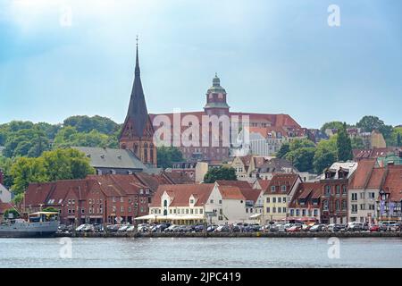 Flensburg, 25. Juli 2022: Flensburg an der Fjord, Stadtbild mit der St. Marien Kirche, dem alten Gymnasium und Stadthäusern unter trübblauem Himmel Stockfoto