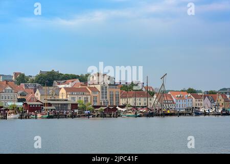 Flensburg, 25. Juli 2022: Museumshafen und alte Werft am Fjord, Stadtbild mit Stadthäusern unter einem trüben blauen Himmel, Kopierraum, se Stockfoto