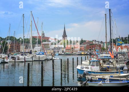 Flensburg, 25. Juli 2022: Altes Stadtbild mit St. Marien Kirche hinter dem Yachthafen mit Segelbooten, am Fjord an der Ostsee Stockfoto