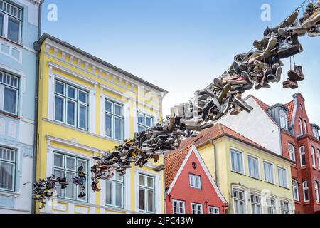 Flensburg, 25. Juli 2022: Alte Schuhe hängen an einem Seil zwischen den Häusern gegenüber der Einkaufsstraße Norderstraße, Wahrzeichen und Tourist-Attr Stockfoto