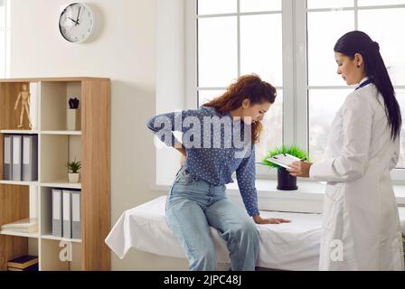 Frau beschwert sich beim Arzt über Rücken- oder Nierenschmerzen während der medizinischen Untersuchung im Krankenhauszimmer. Stockfoto