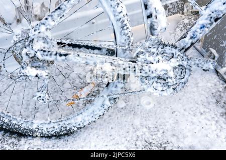 Waschen eines Fahrrads mit einem Schaumstrahl bei einer Autowäsche. Das Fahrrad ist mit Schaumstoff überzogen. Self-Service. Fahrradwartung. Stockfoto