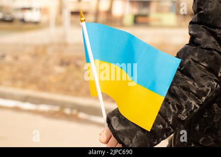 Ukrainisches Kind in der Hand hält die Nationalflagge der Ukraine in der Stadt Dnipro während des Krieges mit Russland, stoppen Sie den Krieg in der Ukraine 2022 Stockfoto