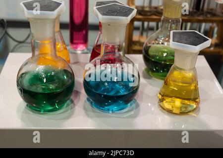 Sphärische Glasflaschen mit Flüssigkeiten verschiedener Farben: Rot, Grün, Gelb und Blau. Stockfoto