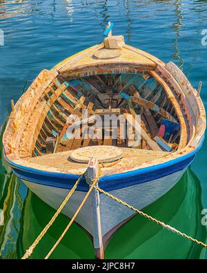 Altes hölzernes verwittertes Fischerboot, das in Griechenland festgemacht ist. Eine alte Batterie im Deck. Stockbild. Stockfoto