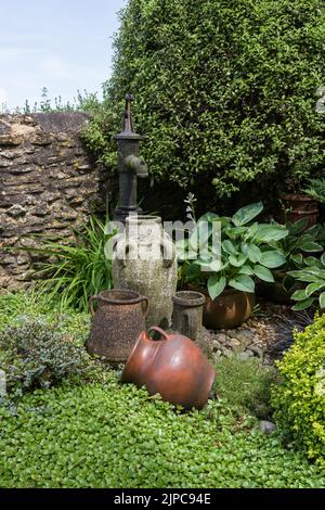 Wasserspiel mit einer altmodischen handbetriebenen Wasserpumpe und Steinbehältern in einem Dorfgarten, Gayton, Northamptonshire, Großbritannien Stockfoto