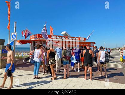 Zandvoort, Niederlande - August 12. 2022: Holländische Uferpromenade mit typischem Fischverkauf Stand, Menschen stehen, Nordseestrand Hintergrund, blaue s Stockfoto