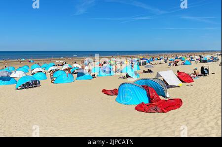 Zandvoort, Niederlande - August 12. 2022: Wunderschöne holländische Küstenstadt entspannender Sandstrand mit typischen blauen Muschelunterkünften, Nordseehorizont, Sommer Stockfoto