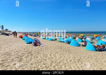 Zandvoort, Niederlande - August 12. 2022: Wunderschöne holländische Küstenstadt entspannender Sandstrand mit typischen blauen Muschelunterkünften, Nordseehorizont, Sommer Stockfoto