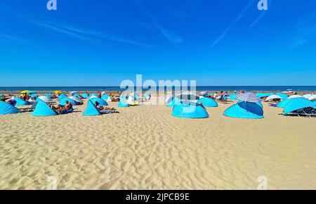 Zandvoort, Niederlande - August 12. 2022: Wunderschöne holländische Küstenstadt entspannender Sandstrand mit typischen blauen Muschelunterkünften, Nordseehorizont, Sommer Stockfoto
