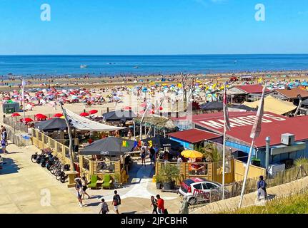 Zandvoort, Niederlande - August 12. 2022: Blick von den Dünen auf den überfüllten holländischen Nordseestandstrand am sonnigen Sommerwochenende Stockfoto