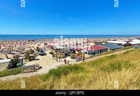 Zandvoort, Niederlande - August 12. 2022: Blick von den Dünen auf den überfüllten holländischen Nordseestandstrand am sonnigen Sommerwochenende Stockfoto