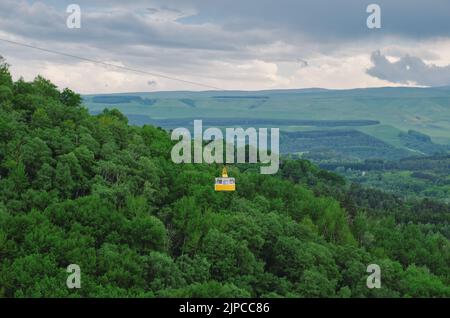 Gelbe Hütte der Seilbahn über dem Wald. Seilbahn über die grünen Hügel. Nationalpark in Kislowodsk, Russland. Stockfoto