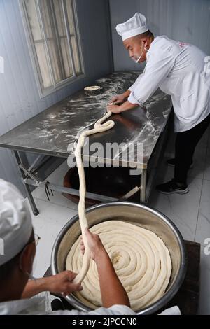 (220817) -- LUONAN, 17. August 2022 (Xinhua) -- Li Changman (L) und sein Sohn Li Nianping machen hohle Nudeln im Dorf Meidi der Gemeinde Bao'an im Landkreis Luonan der Stadt Shangluo, nordwestlich der Provinz Shaanxi, 16. August 2022. Li Changman, ein 66-jähriger Dorfbewohner des Dorfes Meidi, hat seit seiner Jugend die einzigartigen Fähigkeiten zur Herstellung von Hohlnudeln erlernt. Er ist der Erbe von Luonan handgefertigten heiligen Nudelherstellung Fähigkeiten, die als ein provinzielles immaterielles Kulturerbe aufgeführt ist. Er ermutigte sein Kind, diese Kunst zu erlernen, und lehrte die Dorfbewohner auch, ihr Einkommen zu erhöhen. ( Stockfoto