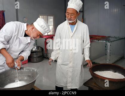 (220817) -- LUONAN, 17. August 2022 (Xinhua) -- Li Changman (R) und sein Sohn Li Nianping bereiten sich auf die Herstellung von Hohlnudeln im Dorf Meidi der Gemeinde Bao'an im Landkreis Luonan der Stadt Shangluo, nordwestlich der chinesischen Provinz Shaanxi, am 16. August 2022 vor. Li Changman, ein 66-jähriger Dorfbewohner des Dorfes Meidi, hat seit seiner Jugend die einzigartigen Fähigkeiten zur Herstellung von Hohlnudeln erlernt. Er ist der Erbe von Luonan handgefertigten heiligen Nudelherstellung Fähigkeiten, die als ein provinzielles immaterielles Kulturerbe aufgeführt ist. Er ermutigte sein Kind, diese Kunst zu erlernen, und lehrte die Dorfbewohner auch, diese Kunst zu erhöhen Stockfoto