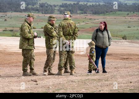 Puckapunyal, Australien, 17. August 2022. Die junge Maddie aus Puckapunyal prüft, was ihr Vater in ihrer eigenen Armeeuniform während einer Armee-Feuerkraftdemonstration für Gäste und Familien A Puckapunyal Range in Victoria macht. Quelle: Michael Currie/Speed Media/Alamy Live News Stockfoto