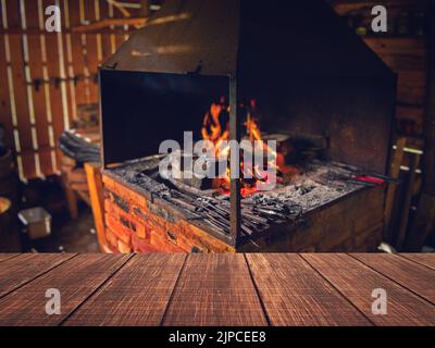 Das Innere einer alten Schmiede. Helles Feuer, das im Ofen brennt. Schmiedet Feuer, das für die Herstellung von Eisenwerkzeugen in Schmieden verwendet wird. Schreibtisch mit freiem Raum und Werkstatt Stockfoto