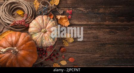 Kürbisse und Herbstlaub auf einem hölzernen Hintergrund. Stockfoto