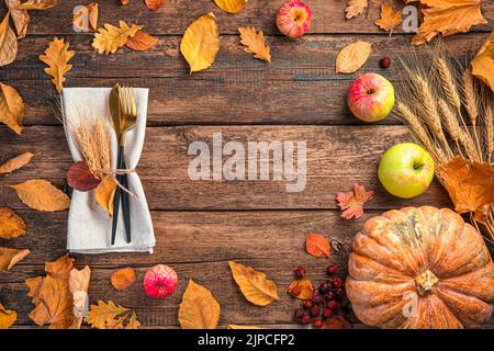 Festlicher Herbsthintergrund mit Besteck, Kürbis, Äpfeln und Herbstlaub. Stockfoto