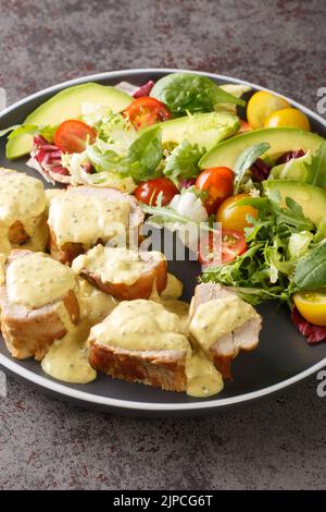 Gebratenes Schweinefilet mit Senfsahnesauce und frischem Gemüsesalat in Nahaufnahme auf einem Teller auf dem Tisch. Vertikal Stockfoto