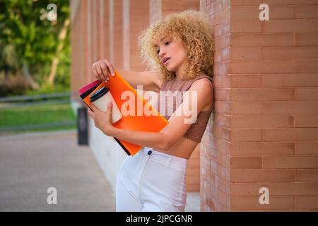 Junge brasilianische Universitätsstudentin, die bei einem Kaffee gegen die Wand studiert. Stockfoto