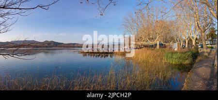 Menschen, die die Wintersonne über dem Pier-Restaurant am See von Banyoles, Girona, Katalonien, Spanien genießen Stockfoto