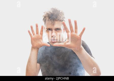 Gruselige Nacht. Verängstigte, gestresste junge Mann mit verschiedenen Emotionen isoliert auf weißem Hintergrund mit Wolken aus Rauch. Stockfoto