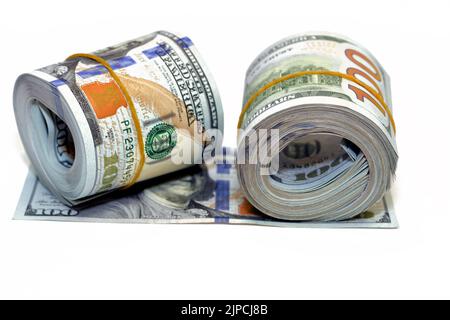 Pakete von Geldrollen von Dollar isoliert auf weißem Hintergrund, Stapel von hundert Dollar amerikanische Geldscheine aufgerollt mit Gummibändern Witz Stockfoto