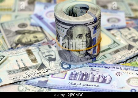 American Money roll with a Band on a pile of American Dollar Geldscheine American Cash Money Banknoten mit Saudi-Arabien riyals Geldscheine und New Emir Stockfoto