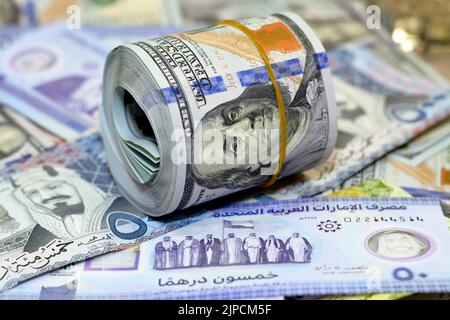 American Money roll with a Band on a pile of American Dollar Geldscheine American Cash Money Banknoten mit Saudi-Arabien riyals Geldscheine und New Emir Stockfoto