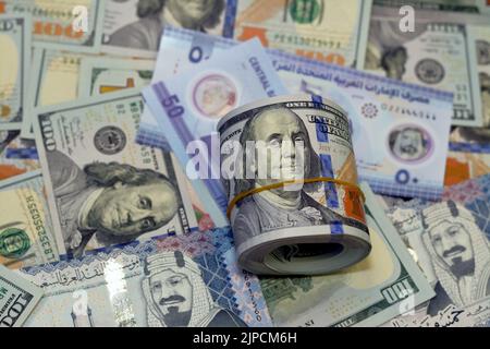 American Money roll with a Band on a pile of American Dollar Geldscheine American Cash Money Banknoten mit Saudi-Arabien riyals Geldscheine und New Emir Stockfoto