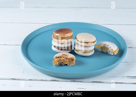 Stapel Macarons gefüllt mit Dulce de leche und Schokoladenganache, neben zwei Macarons mit Bissen. Stockfoto