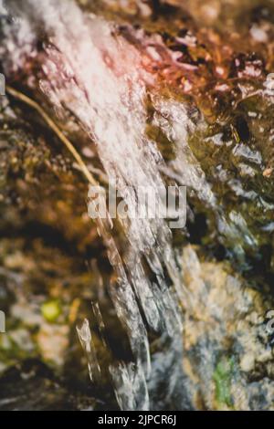 Wasserfall fließt und leuchtet auf farbigen Felsen Stockfoto