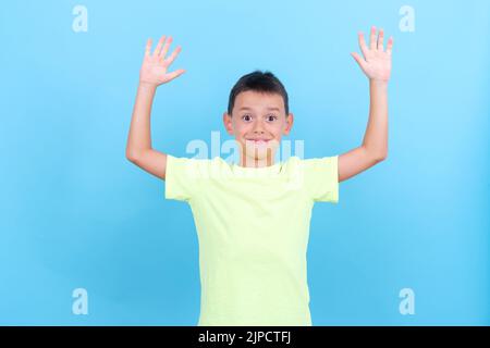 Der 8-jährige Junge hebt seine Hände in einer überraschenden Geste Stockfoto