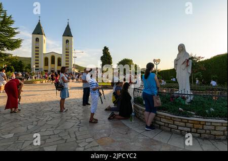 Die Menschen beten vor der Statue der Jungfrau Maria, der Königin des Friedens, vor der Kirche des hl. Jakobus in Medjugorje, Bosnien und Herzegowina. Stockfoto