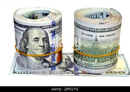 Pakete von Geldrollen von Dollar isoliert auf weißem Hintergrund, Stapel von hundert Dollar amerikanische Geldscheine aufgerollt mit Gummibändern Witz Stockfoto