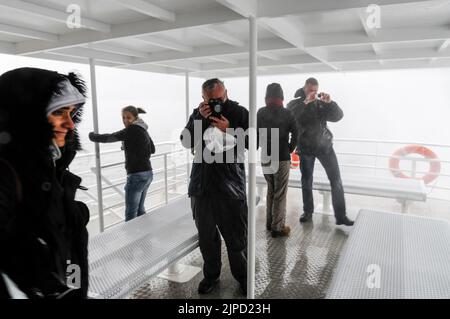 Einige der Bordtouristen waren mutig genug, den mächtigen Spray zu erleben, als das Cruiser-Schiff näher an den 155 m hohen Stirling Falls auf M heranragt Stockfoto