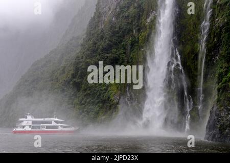 Das Kreuzschiff Pride of Milford of Red Ferries liegt näher an den 155 m hohen Stirling Falls, zum Wohle der Touristen am Milford Sound in Fiordland Stockfoto